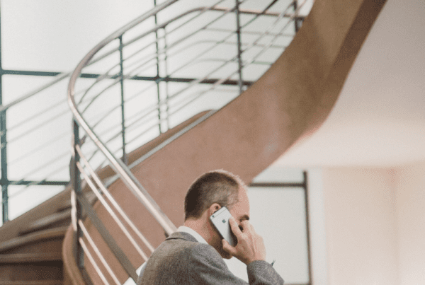 Man on phone standing in front of smart film, frosted windows and a staircase