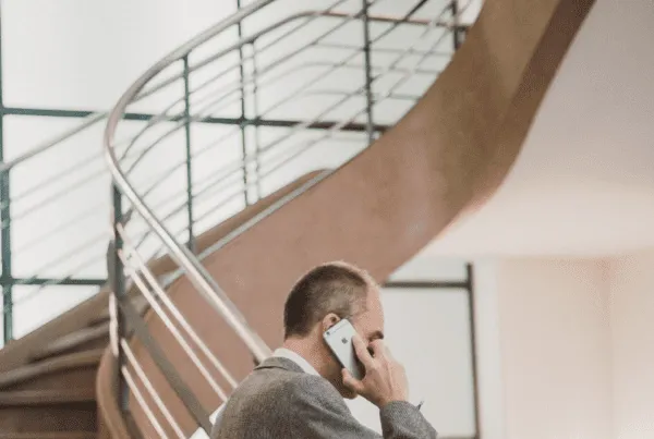 Man on phone standing in front of smart film, frosted windows and a staircase