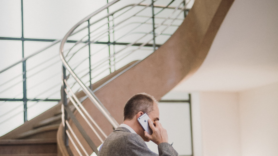 Man on phone standing in front of smart film, frosted windows and a staircase