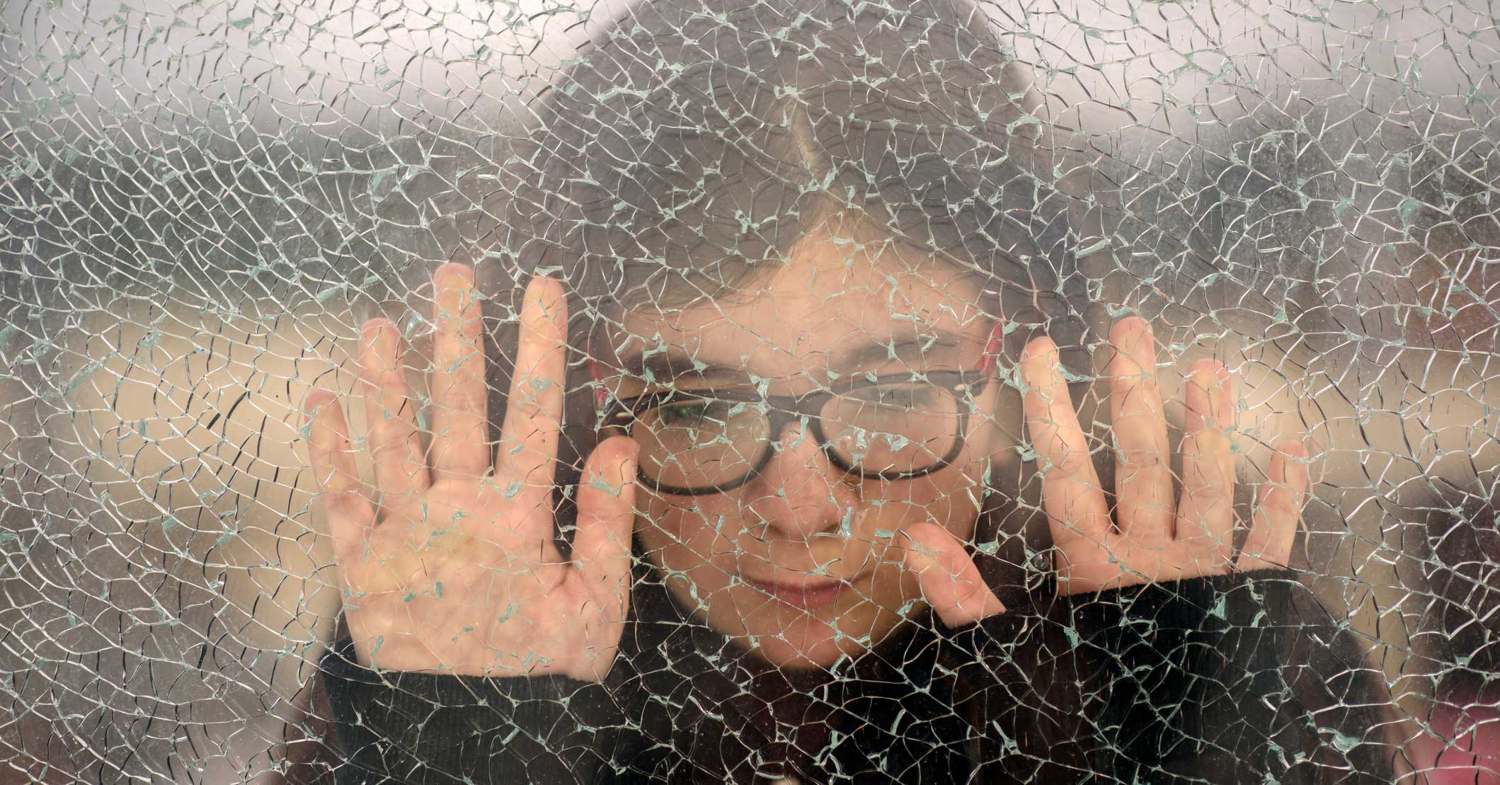 A person leaning up against a frosted glass window.