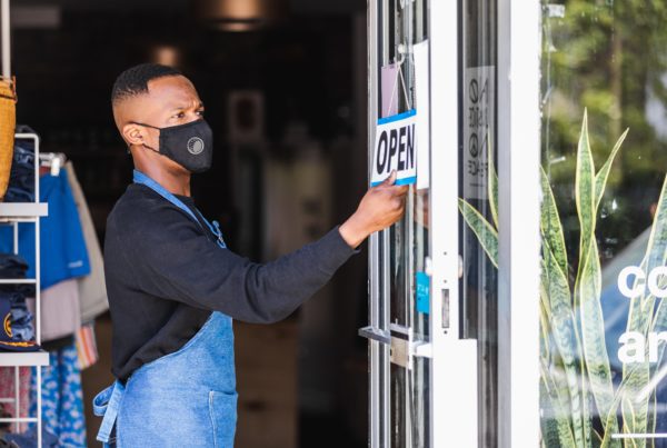 A man flipping the the sign of his retail store to open.