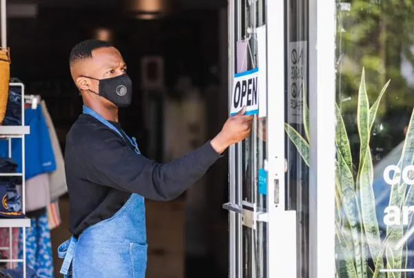 A man flipping the the sign of his retail store to open.