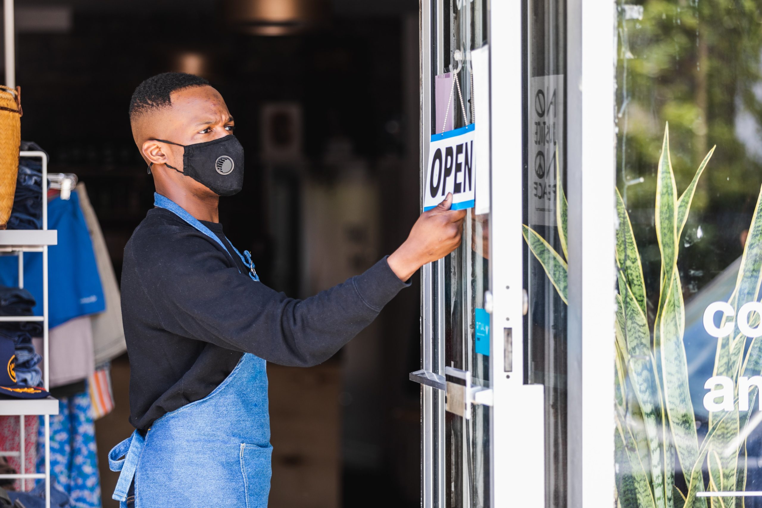 A man flipping the the sign of his retail store to open.