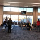 The interior of an airport facing the window with passengers sitting down ready to board a flight.