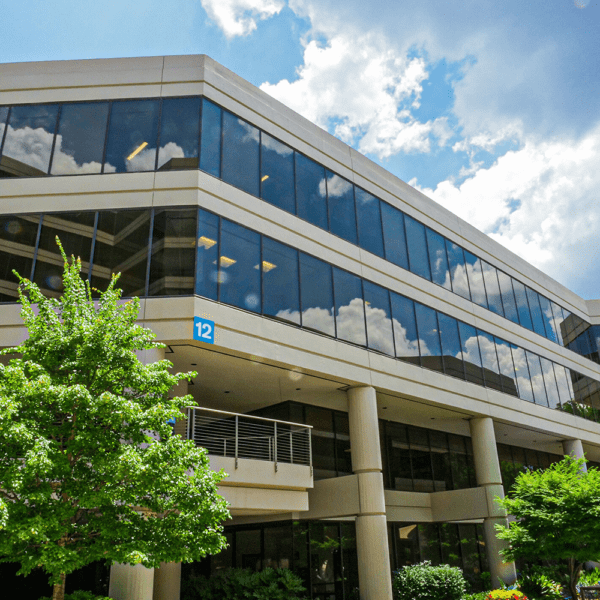 A large office building with overhanging stories and NGS installed glass.