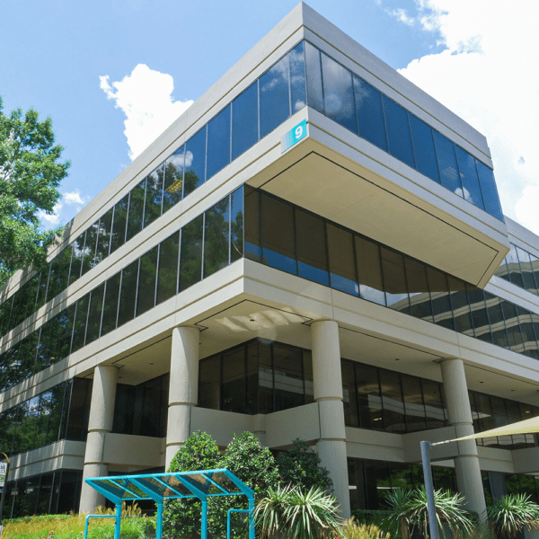 A large office building with overhanging stories and NGS installed glass.