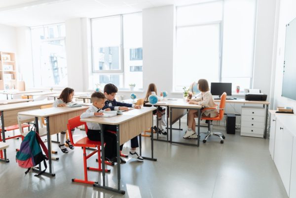 Children in a classroom with a lot of windows to illustrate energy efficiency in school buildings