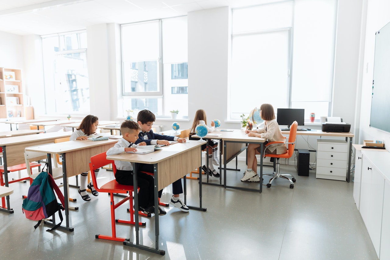 Children in a classroom with a lot of windows to illustrate energy efficiency in school buildings