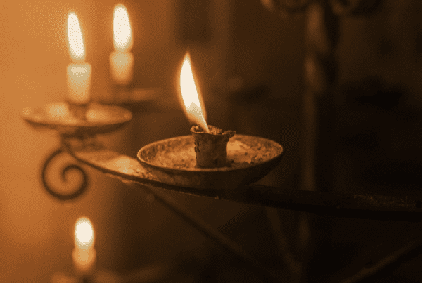 Lit prayer candles in a dim room in a place of worship