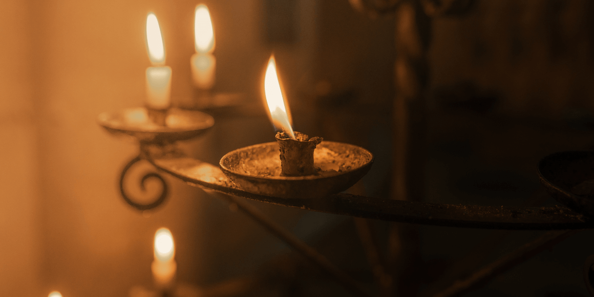 Lit prayer candles in a dim room in a place of worship