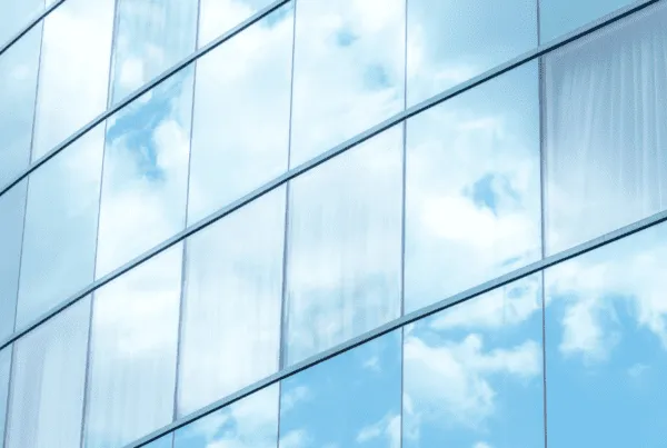 Corporate building with reflective window film mirroring a partially cloudy sky